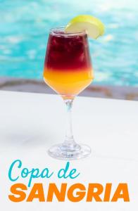 a drink in a glass next to a swimming pool at HOTEL CLUB MORAZAN in San Lorenzo