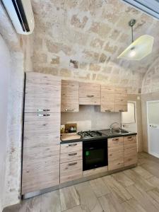 kuchnia z drewnianymi szafkami i kuchenką w obiekcie Casa Monopoli w mieście Monopoli