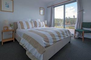 1 dormitorio con cama grande y ventana grande en Merino Cottage Meadowbank Lake, en Ellendale