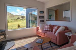 sala de estar con sofá y ventana grande en Merino Cottage Meadowbank Lake, en Ellendale