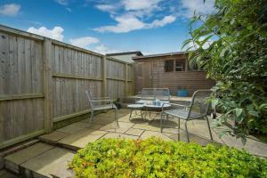 d'une terrasse avec une table, des chaises et une clôture. dans l'établissement Windward cottage, a great 3bed house in Cowes, à Cowes