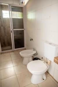 a white bathroom with a toilet and a shower at Eleven in Posadas