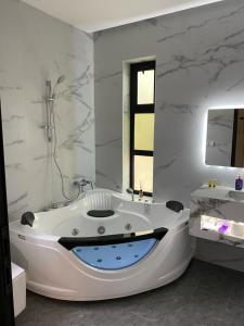 Baño blanco con bañera y lavamanos en شاليهات سيليا الفندقية, en Al Mubarraz