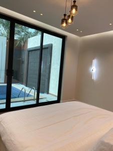 a bedroom with a large bed and a large window at شاليهات سيليا الفندقية in Al Mubarraz