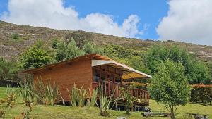 a small wooden cabin with a hill in the background at Mirador Valeisa in Guatavita