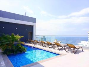 a pool on the roof of a building with chairs at Exclusivos apartasuites Ambar Roca - Rodadero in Santa Marta +28 photos