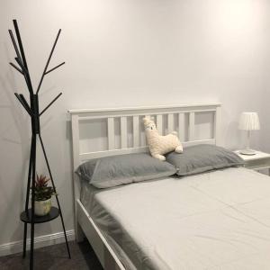 a white bed with a teddy bear on top of it at 舒适的2卧公寓，带室内泳池和桑拿 in Sydney