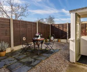 a patio with a table and chairs in front of a fence at Holly Cottage in Cartmel