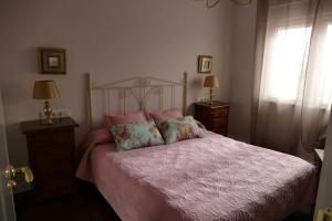 1 dormitorio con 1 cama con sábanas y almohadas rosas en 2 bedrooms chalet with private pool terrace and wifi at Villamayor en Villamayor