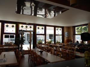 a dining room with tables and chairs and windows at Hotel Du Jura in Audincourt