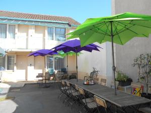 a wooden table with chairs and umbrellas on a patio at Hotel Du Jura in Audincourt