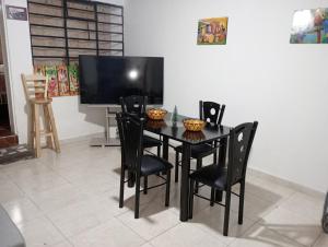 a black dining room table with black chairs and a tv at Apartamento Centro histórico in Bogotá
