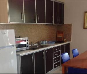 a kitchen with black cabinets and a sink and a microwave at George’s Apartment in Orikum