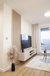 uma sala de estar branca com uma televisão e uma mesa em KOBIELA APARTMENTS Dębowe Tarasy em Katowice