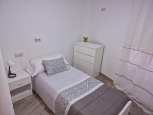 a small bedroom with a bed and a dresser at La de Fredyy - Tres Marias Apartments in Redondela