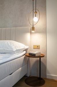 a bed with a table next to a bed with a lamp at KOBIELA APARTMENTS Dębowe Tarasy in Katowice