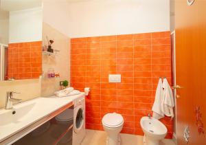 La salle de bains est pourvue de carrelage orange, de toilettes et d'un lavabo. dans l'établissement Bologna Fair Expo Apartment, à Bologne