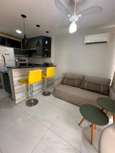 a kitchen and living room with yellow chairs and a couch at Flat Praiano Aconchegante in Cabedelo