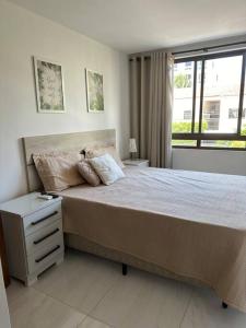 um quarto com uma cama grande e uma janela em Flat Praiano Aconchegante em Cabedelo