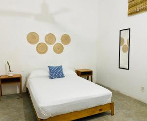 1 dormitorio con 1 cama blanca y 2 mesas en Casa Karma, en Puerto Escondido