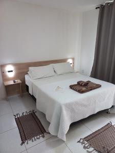 a bedroom with a large white bed with a towel on it at AYRE GOSTOSO POUSADA in São Miguel do Gostoso