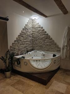 Studio de charme en pleine nature. في Beaux: حوض استحمام كبير في غرفة بجدار حجري