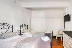 a white bedroom with two beds and a tv at Centro Storico di Genova a 15 minuti, Sweet Home in Genoa
