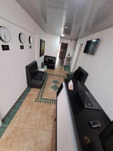 a living room with two chairs and a desk and a clock at Casa Hotel Mónaco in Bogotá