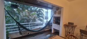 a hammock in a room with a large window at Belo apto agradável em Lagoa da Conceição DET0024 in Florianópolis
