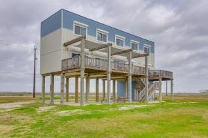 a blue building with wooden posts in a field at Boardwalk to Beach Ocean-View Surfside Home! in Surfside Beach