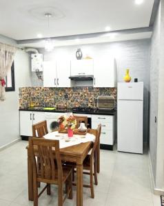 a kitchen with a table and chairs and a refrigerator at Appartement de luxe in Kenitra