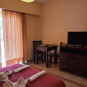 een slaapkamer met 2 bedden, een bureau en een televisie bij Hotel El Sauce in Santa Rosa de Calamuchita