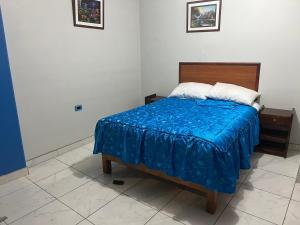 een slaapkamer met een bed met een blauwe deken bij Posada de Percybal Mirador in Puno