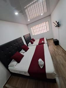 a bedroom with a large bed with red pillows at Casa Hotel Mónaco in Bogotá