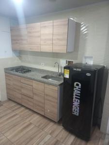 a kitchen with a black refrigerator and a sink at Casa Hotel Mónaco in Bogotá