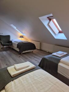 una camera da letto mansardata con due letti, una sedia e un lucernario di Hotel Hafnarfjall a Borgarnes