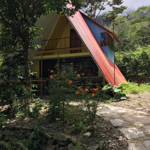 una casa con un tetto rosso con dei fiori davanti di Madera Verde Ecolodge a Maranura