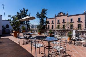 un patio con mesas, sillas y una sombrilla en Hotel Refugio Victoria en Morelia