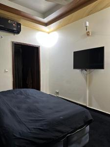 a bedroom with a bed and a flat screen tv on the wall at HHH Brothers House in Rawalpindi