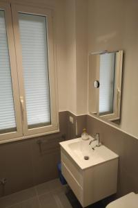 un bagno con lavandino bianco e due finestre di Apartment Via Raffaele Balestra a Roma