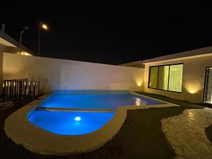 una piscina por la noche en una casa en HAFAL Resort شاليهات هافال, en Riad