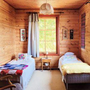 dwa łóżka w drewnianym domku z oknem w obiekcie Villa Jääskelä Hanko - koko talo w mieście Hanko