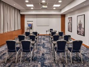 una sala de conferencias con mesas y sillas y una pantalla de proyección en Radisson Blu Hotel Krakow, en Cracovia