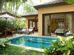 a swimming pool in front of a villa at Mövenpick Asara Resort & Spa Hua Hin in Hua Hin