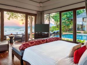 a bedroom with a large bed with a view of the ocean at Mövenpick Asara Resort & Spa Hua Hin in Hua Hin