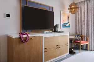 ホノルルにあるOUTRIGGER Waikiki Paradise Hotelのドレッサーの上にテレビが備わる部屋