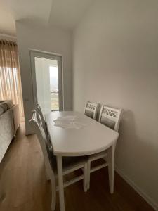 una mesa y sillas blancas en una habitación con ventana en Shehu’s Apartament en Tirana