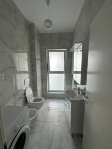 baño con 2 lavabos, aseo y ventana en Shehu’s Apartament en Tirana