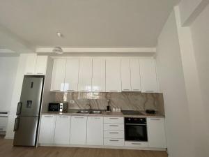 cocina con armarios blancos y nevera de acero inoxidable en Shehu’s Apartament en Tirana