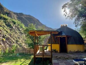 une yourte avec une terrasse couverte en bois en face d'une montagne dans l'établissement ammonite aventura del Maipo casa entera reserva 50 por ciento anticipado, à San José de Maipo